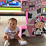 baby, child, infant, birthday, party, number_one, decoration, pink, cow, cute, outdoor, concrete_floor, table, sitting, shoes, white_clothing, celebration, banner, grass, playground