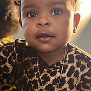 Sage is registered to the contest to win money with this photo: child, toddler, leopard_print, bow, necklace, jewelry, curly_hair, face, portrait, indoor, cosmetics, bottle, reflection, mirror, fashion, cute, eyes, skin, expression, person