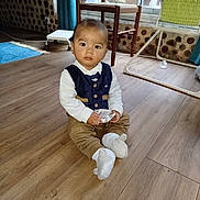 Haroun a rejoint le concours — aidez-le/la à gagner de superbes lots ! baby, child, indoor, floor, wooden_floor, vest, sitting, holding, box, window, chair, curious, person, sock, footwear, home_interior, furniture, greenery, curtain, natural_light