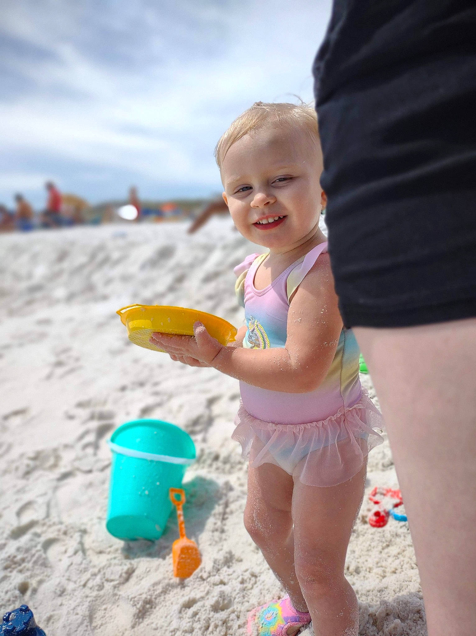 Audrey is registered to the contest to win money with this photo: beach, bucket, child, cloud, event, fun, happy, hat, human_leg, joy, leisure, people, people_in_nature, people_on_beach, person, recreation, sand, shorts, sky, smile