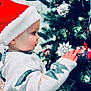 adult, baby, cap, christmas, christmasdecorations, christmastree, christmastreeornaments, clothing, face, festival, hat, head, male, man, nature, openingpresent, outdoors, person, snow