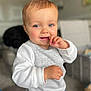 baby, babylaughing, biting, blonde, bodypart, clothing, eating, face, finger, food, hair, hand, happy, head, longsleeve, person, photography, portrait, sleeve, smile