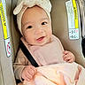 baby, smiling, infant, car_seat, headband, pink_clothing, blanket, child, cute, happy, face, person, seatbelt, child_safety, indoors, portrait, young_child, baby_girl, closeup, warm_colors