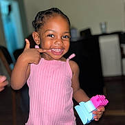 Lénaëlle a rejoint le concours — aidez-le/la à gagner de superbes lots ! bokeh, braided_hair, building_blocks, candid, child, cute, dark_skin, eyelashes, finger_gesture, furniture, happy, indoor, living_room, pink_dress, portrait, ribbed_top, smile, teeth, toddler, toy