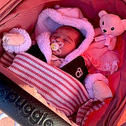 Xensia is registered to the contest to win money with this photo: baby, sleeping, pacifier, blanket, mittens, stroller, teddy_bear, pink, cozy, child, infant, cute, warm_clothing, soft_toys, portrait, resting, indoor, bundle, headwear, comfort
