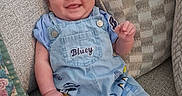Henry is registered to the contest to win money with this photo: baby, baby_face, blue_clothing, chair, child, cushion, floral_cushion, furniture, happy, home, indoor, infant, overalls, patterned_fabric, photography, portrait, raised_hand, shorts, sitting, smiling
