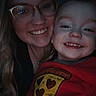 Ricky is registered to the contest to win money with this photo: woman, child, toddler, glasses, smile, face, portrait, red_clothing, pizza_graphic, happy, indoor, dark_background, closeup, casual, people, person, headshot, cute, love, family