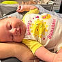 Hadley is registered to the contest to win money with this photo: arm, baby, blanket, child, cozy, cute, happy, human, indoor, infant, onesie, person, resting, sleeping, smile, soft, sun_graphic, text_on_clothing, white, yellow