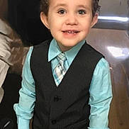 James joined the competition — help win amazing prizes! child, boy, smile, curly_hair, vest, tie, dress_shirt, indoor, floor, wooden_floor, happy, portrait, person, clothing, formal_wear, cute, standing, young, fashion, small