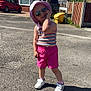 asphalt, car, child, daytime, fence, house, outdoor, pink_shorts, playful_pose, residential_area, shadow, sidewalk, smiling, street, sunglasses, sunhat, sunny, tank_top, toddler, white_sneakers