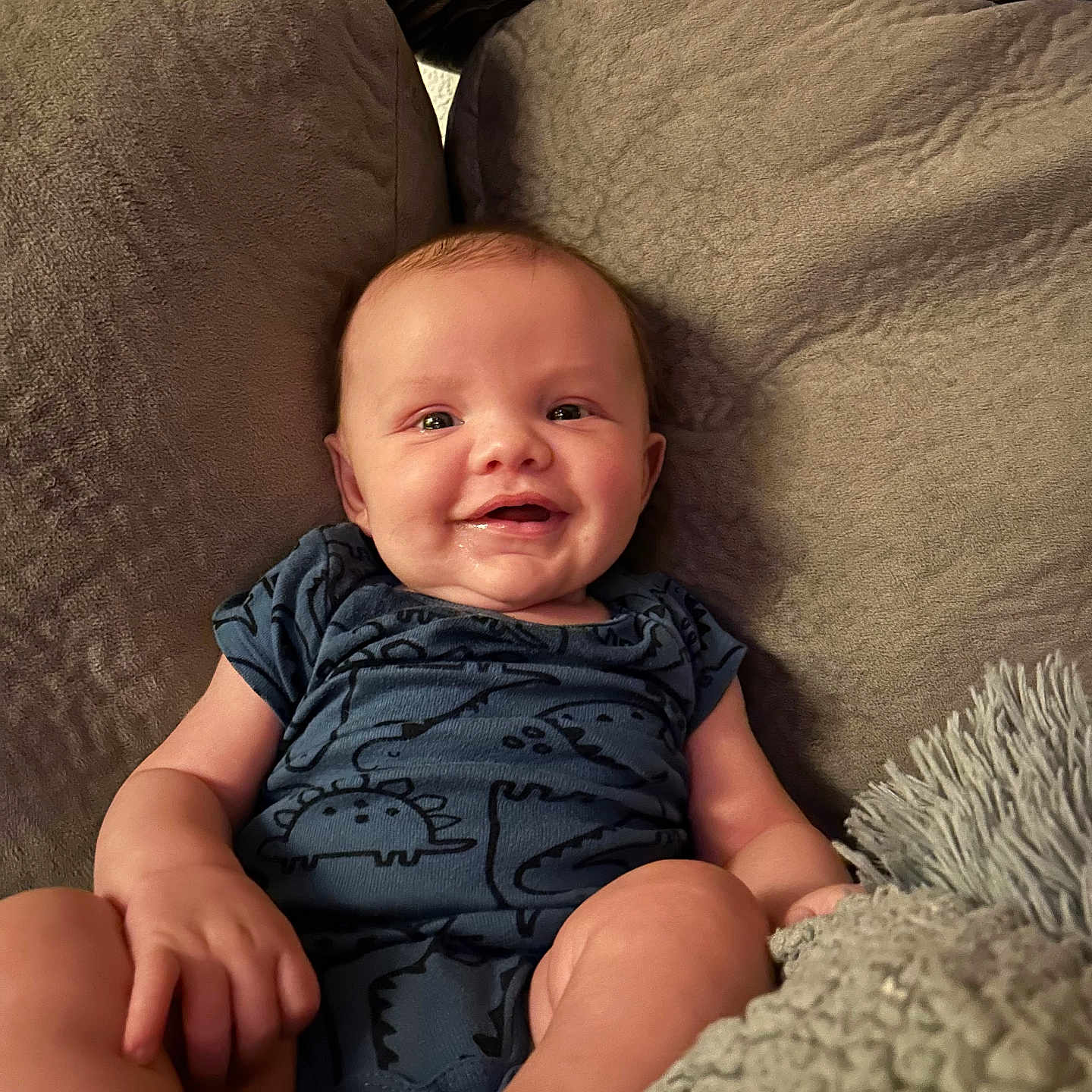 Ezekiel is registered to the contest to win money with this photo: baby, babylaughing, bodypart, clothing, couch, cushion, face, finger, furniture, hand, happy, head, homedecor, newborn, person, photography, portrait, sitting, smile, t_shirt