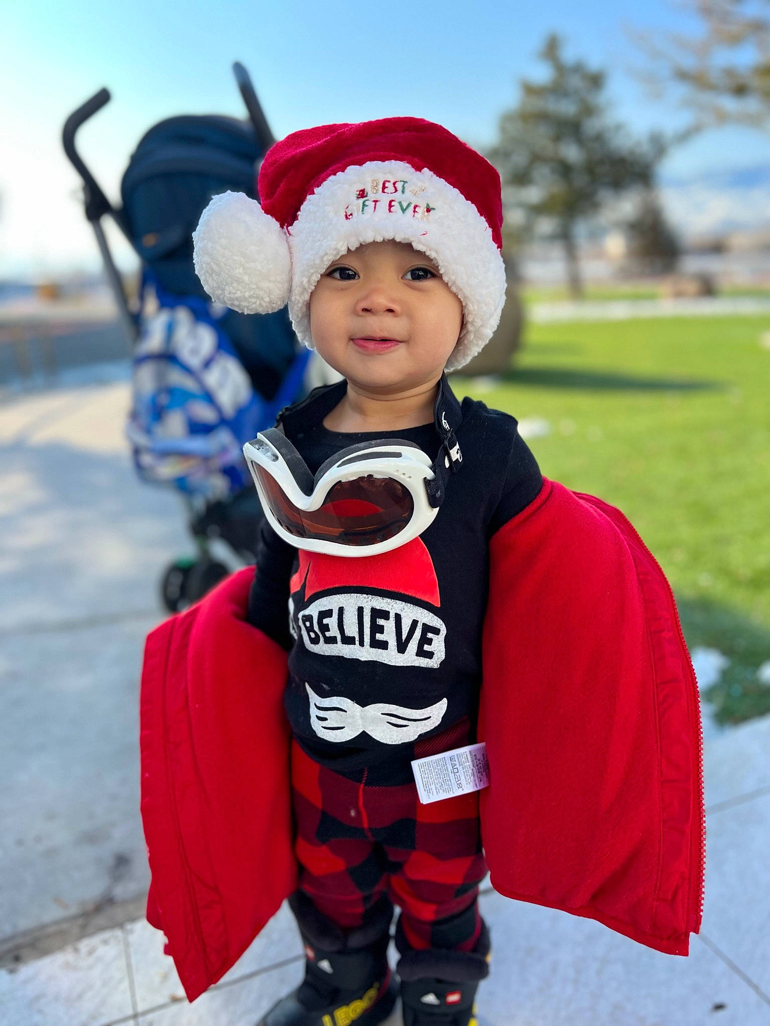 Aiden is registered to the contest to win money with this photo: baby, cap, child, costume_hat, event, fictional_character, fun, glove, happy, hat, headgear, headwear, outerwear, person, personal_protective_equipment, plant, recreation, sky, sleeve, smile