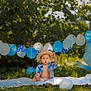 baby, boy, birthday, balloons, straw_hat, blue_shirt, blanket, outdoor, grass, greenery, celebration, number_one_balloon, sunlight, child, happy_birthday_banner, party, nature, summer, cute, portrait