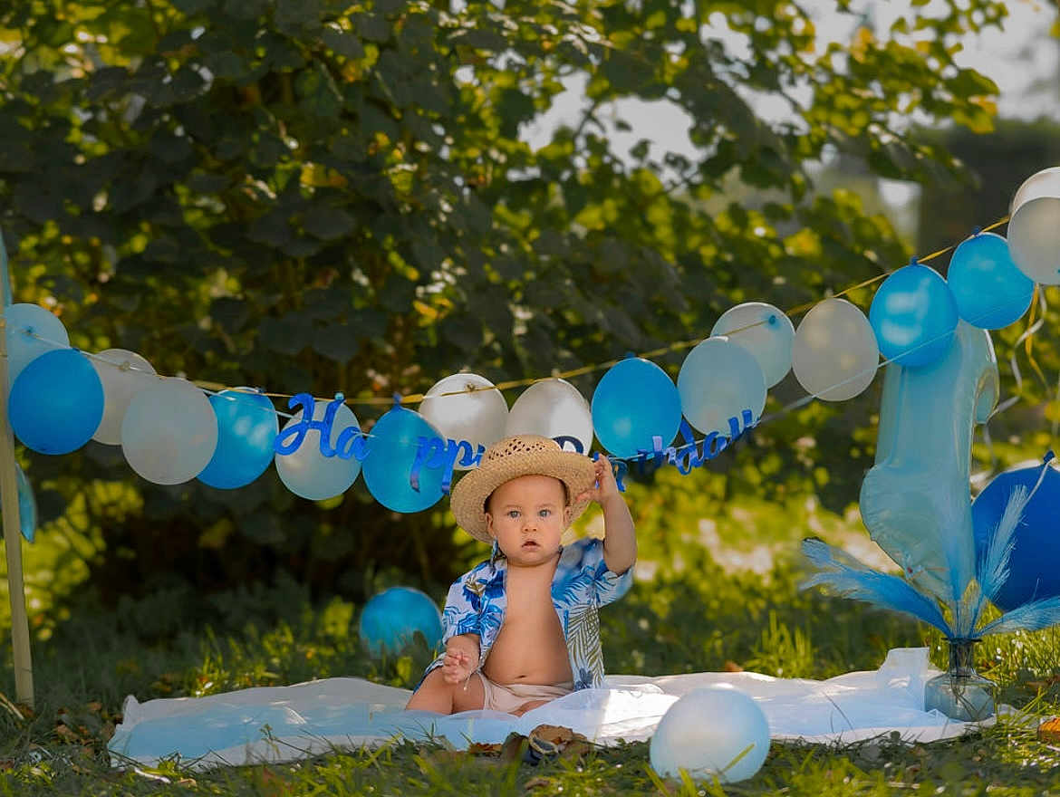 Kalahani participe au concours pour gagner de l'argent avec cette photo : baby, boy, birthday, balloons, straw_hat, blue_shirt, blanket, outdoor, grass, greenery, celebration, number_one_balloon, sunlight, child, happy_birthday_banner, party, nature, summer, cute, portrait