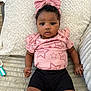 baby, infant, child, pink_bow, pink_shirt, stars_pattern, black_shorts, blanket, soft_texture, indoor, portrait, cute, curious, face, hands, legs, lying_down, comfortable, young_child, headband