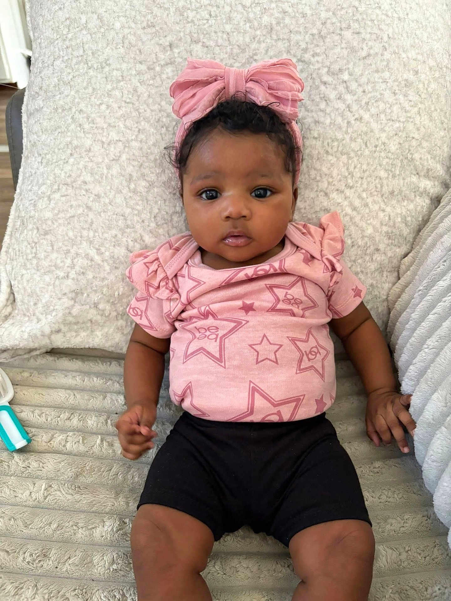 Amouraa is registered to the contest to win money with this photo: baby, infant, child, pink_bow, pink_shirt, stars_pattern, black_shorts, blanket, soft_texture, indoor, portrait, cute, curious, face, hands, legs, lying_down, comfortable, young_child, headband