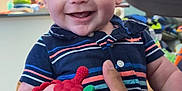 Luka is registered to the contest to win money with this photo: baby, child, smiling, happy, indoor, person, face, hand, toy, teether, clothing, striped_shirt, holding, closeup, portrait, infant, cute, cheerful, playful, home