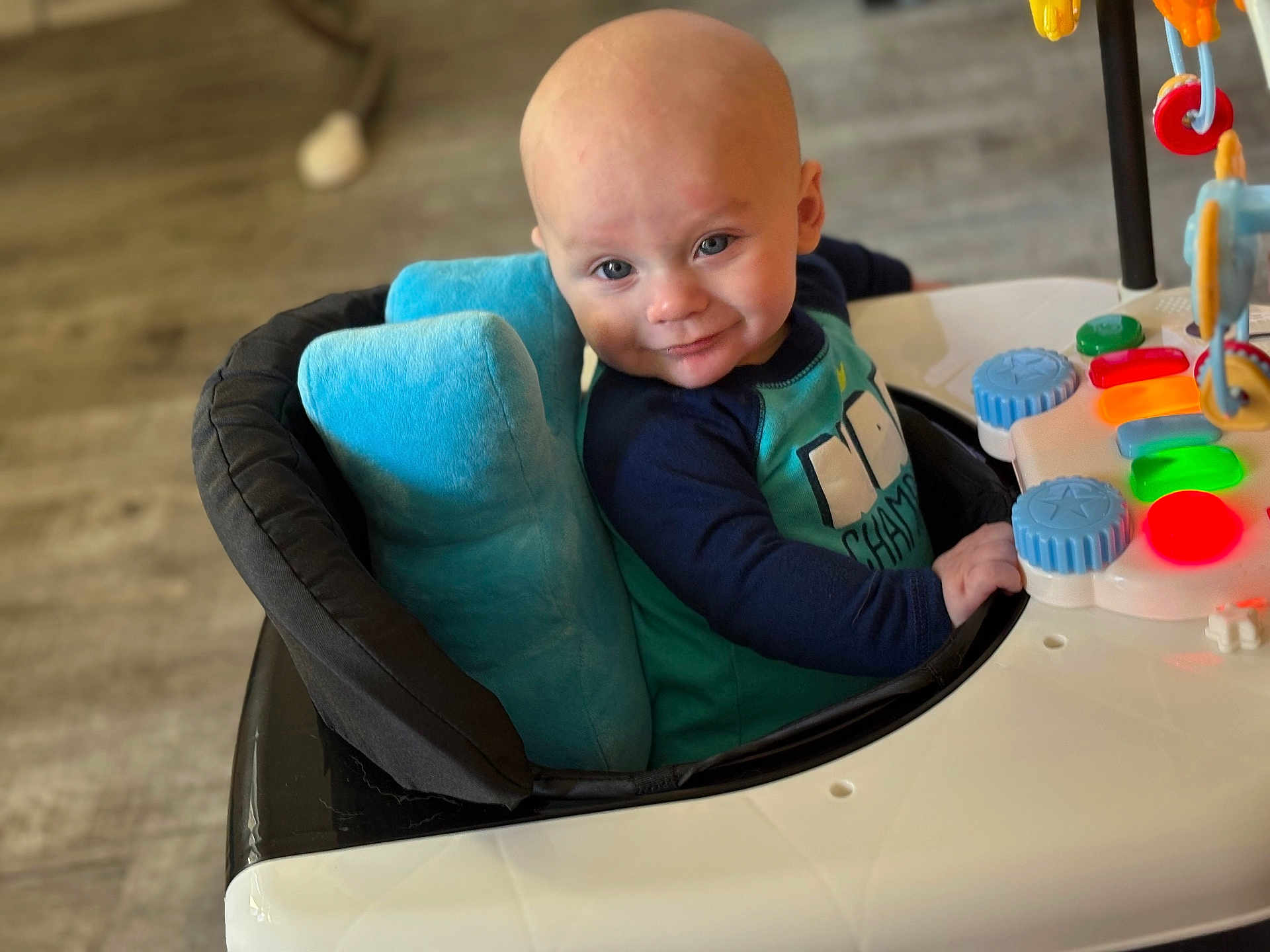 Luka joined the competition — help win amazing prizes! baby, walker, toy, smile, child, blue_cushion, indoor, play, face, person, cute, happy, sitting, colorful, buttons, floor, clothing, head, expression, infant