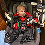 baby, black, blanket, car_seat, child, clothing, cute, face, footwear, head, holding, indoor, infant, pacifier, patterned, plush, red, seatbelt, sitting, toy