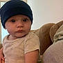 Luka joined the competition — help win amazing prizes! baby, infant, child, beanie, hat, onesie, couch, sofa, indoor, person, hand, seated, looking, curious, casual_clothing, home, portrait, young_child, support, expression