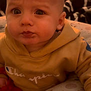 Luka is registered to the contest to win money with this photo: baby, blanket, casual_clothing, child, closeup, curious, cushion, expression, face, furniture, hoodie, indoor, infant, person, portrait, red_toy, seated, soft_lighting, toy, yellow_clothing