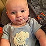 Luka is registered to the contest to win money with this photo: baby, infant, child, onesie, elephant, embroidered_text, blue_clothing, smiling, portrait, closeup, cute, person, human, sitting, indoor, soft_lighting, face, eyes, newborn, couch