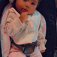 Zailani is registered to the contest to win money with this photo: baby, infant, child, pink_clothing, bib, elephant_design, baby_seat, car_seat, straps, soft_toys, cozy, cute, indoor, portrait, smiling, face, hand, footwear, knitted_booties, curly_hair