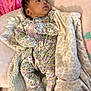 Zailani joined the competition — help win amazing prizes! baby, infant, floral_onesie, blanket, soft_texture, bed, lying_down, face, curious, pink, purple, yellow, green, patterned_clothing, indoor, child, cute, cozy, warm, sleepwear