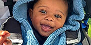 Jayden is registered to the contest to win money with this photo: baby, child, blue_hoodie, smiling, face, stroller, happy, outdoor, clothing, person, portrait, cute, infant, seatbelt, babywear, hood, black_hair, expressive_eyes, sunlight, texture