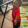 Jayden is registered to the contest to win money with this photo: toddler, child, red_shirt, nike, indoor, carpet, chair, striped_mat, socks, curious, standing, toy, black_shorts, expression, person, floor, home, furniture, baby, playtime