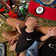 Maverick joined the competition — help win amazing prizes! baby, infant, sleeping, outdoor, picnic, grass, lap, adult, black_onesie, nike, folding_chair, snacks, water_bottle, soda_can, beverage, blanket, tattoo, hands, portrait, relaxed