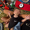 baby, infant, sleeping, outdoor, picnic, grass, lap, adult, black_onesie, nike, folding_chair, snacks, water_bottle, soda_can, beverage, blanket, tattoo, hands, portrait, relaxed
