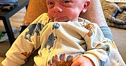 Maverick is registered to the contest to win money with this photo: baby, infant, child, portrait, smiling, sitting, chair, blanket, onesie, clothing, face, eyes, hands, home, indoor, furniture, cozy, colorful, photography, background