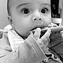 baby, infant, close_up, black_and_white, bib, long_sleeve, hand, face, eyes, indoor, feeding, spoon, curious, cute, child, portrait, young, person, small_hands, soft_background