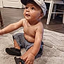 Josiah is registered to the contest to win money with this photo: baby, child, indoor, floor, rug, cap, shorts, sandals, bare_chest, curious, sitting, wood_floor, furniture, bracelet, cute, infant, person, home, playful, expression
