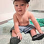 Josiah is registered to the contest to win money with this photo: toddler, child, cap, shirtless, shorts, shoes, rug, floor, indoor, curious, sitting, footwear, bracelet, young_child, baby, barefoot, person, home, casual, playful