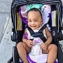 baby, smile, stroller, child, infant, harness, blanket, headband, outdoor, cute, happy, seat, clothing, person, legs, barefoot, purple, black, safety, portrait