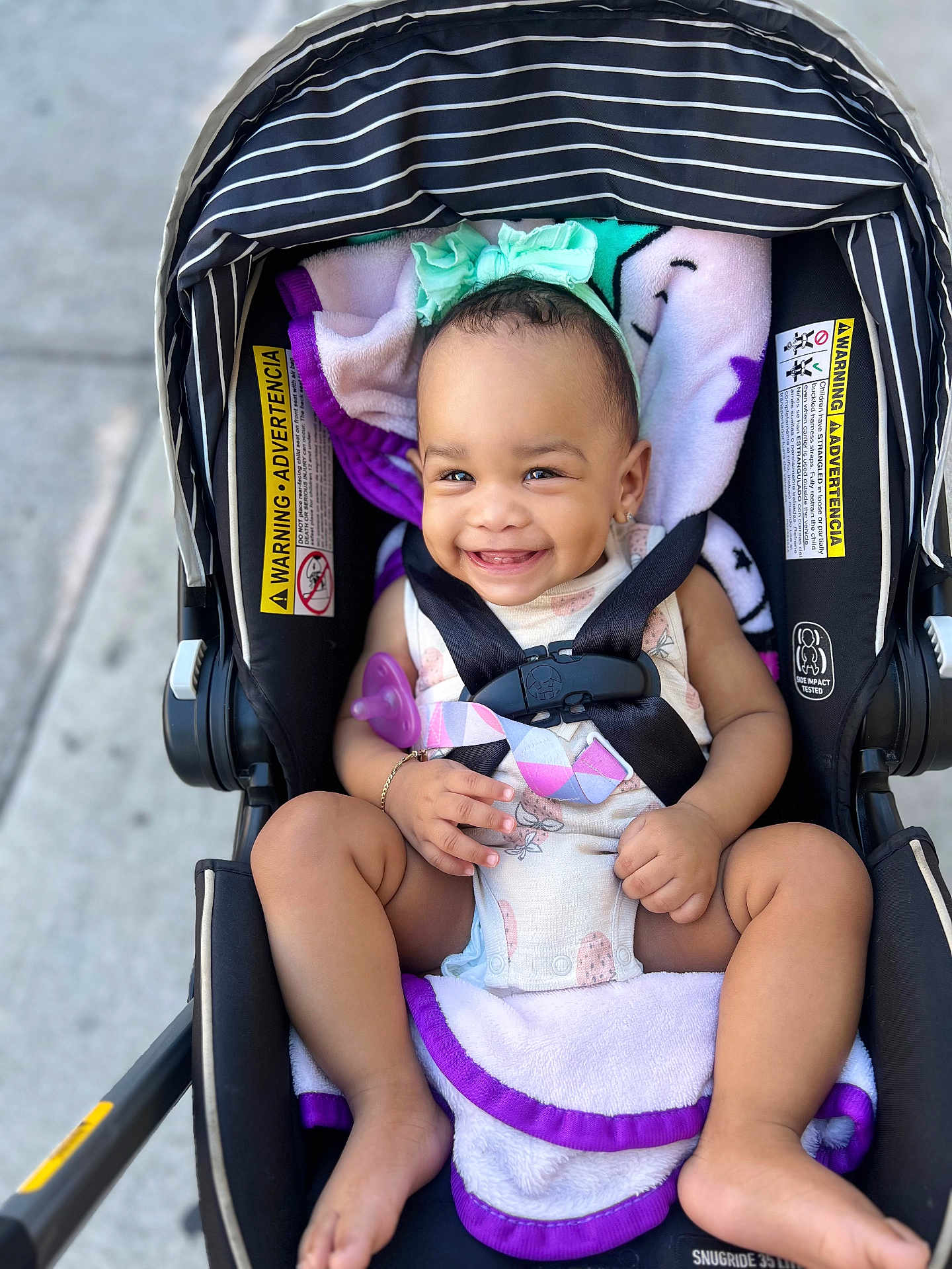 Mieah joined the competition — help win amazing prizes! baby, smile, stroller, child, infant, harness, blanket, headband, outdoor, cute, happy, seat, clothing, person, legs, barefoot, purple, black, safety, portrait
