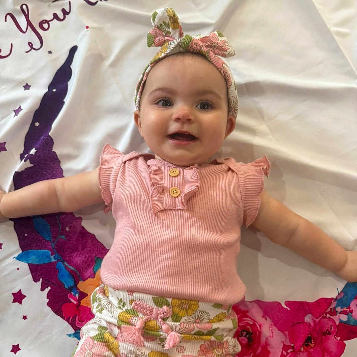 Jorianna joined the competition — help win amazing prizes! baby, blanket, child, colorful, cute, floral_pattern, floral_shorts, happy, headband, headwear, indoors, infant, lying_down, person, pink_top, playful, portrait, smiling, soft_lighting, young_child