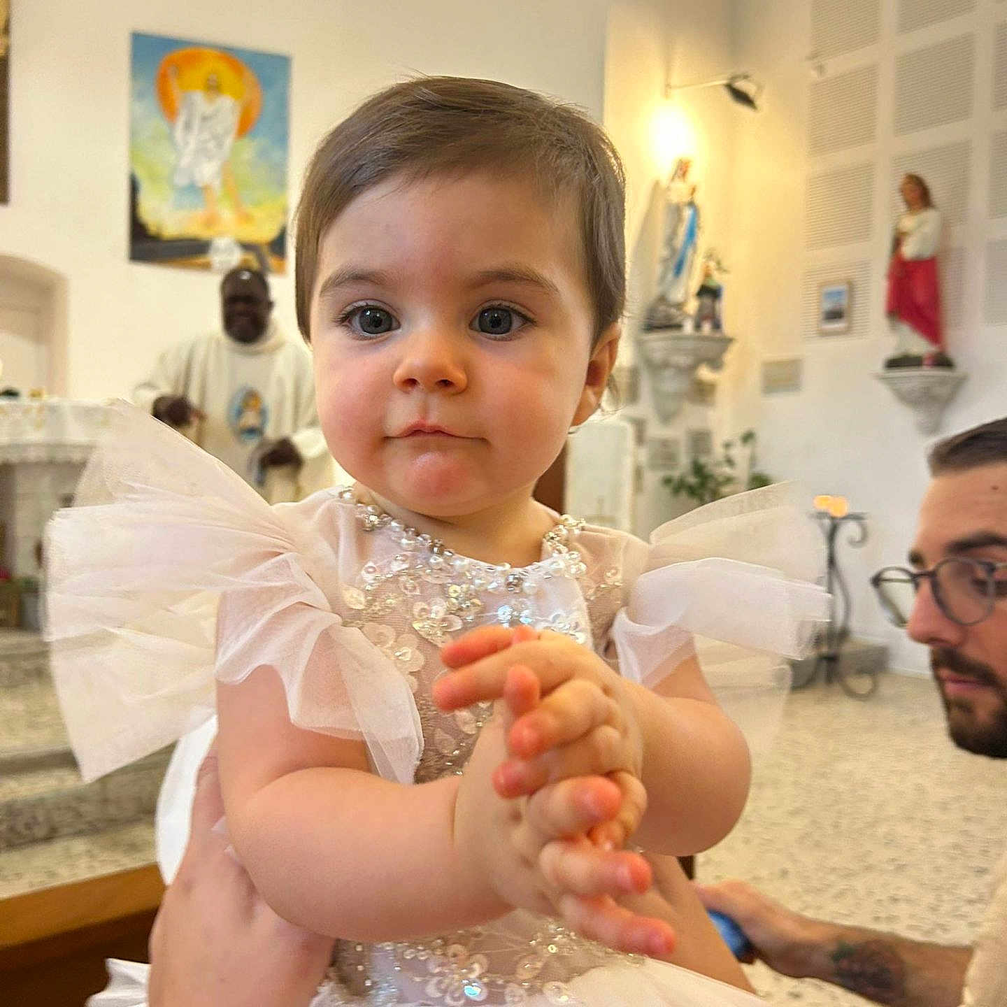 Déa participe au concours pour gagner de l'argent avec cette photo : adult, celebration, ceremony, child, church, clapping_hands, cute, decor, dress, floor, indoor, people, person, portrait, priest, religious, seated, statue, toddler, white_dress