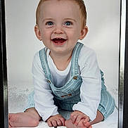 Isaac joined the competition — help win amazing prizes! baby, child, smiling, happy, blue_eyes, overalls, white_shirt, sitting, floor, toes, hands, portrait, cute, infant, crawling_pose, studio_photo, bright, clean_background, young, playful