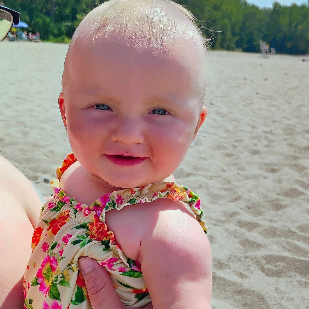 Aero is registered to the contest to win money with this photo: arm, baby, beach, blue_sky, child, cute, floral_dress, happy, head, holding, nature, outdoor, person, portrait, sand, skin, smiling, summer, sunny, trees