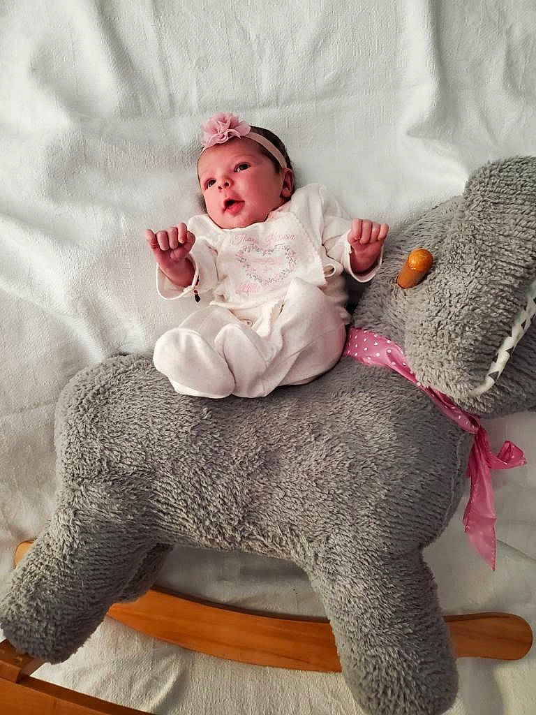 Aurora is registered to the contest to win money with this photo: art, baby, baby_toddler_clothing, child, comfort, crochet, dress, fashion_accessory, fur, grey, headgear, leg, pattern, person, pink, plant, sitting, sleeve, textile, wool