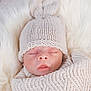 baby, newborn, sleeping, knit_hat, blanket, fur, cozy, portrait, infant, closed_eyes, swaddle, soft_texture, peaceful, lips, nose, eyelashes, headwear, white_background, studio_style, cute