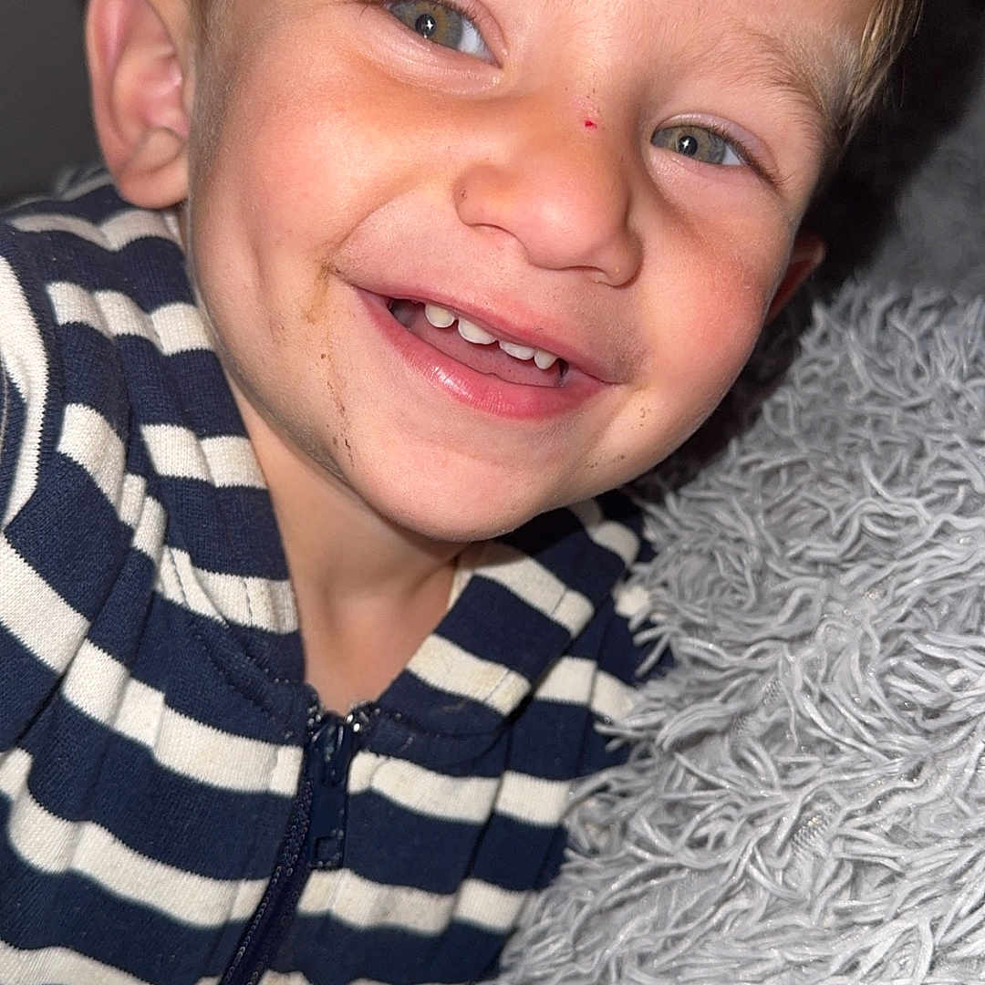 Ayden a rejoint le concours — aidez-le/la à gagner de superbes lots ! baby, blanket, blue_and_white, cheerful, child, close_up, cozy, cute, face, fluffy_texture, happy, hoodie, indoor, person, portrait, smiling, striped_clothing, toddler, young_child, young_kid