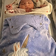 Elya participe au concours pour gagner de l'argent avec cette photo : newborn, baby, sleeping, hospital_bassinet, blanket, unicorn, hat, swaddle, id_card, crib, bassinet, blue_blanket, infant, indoors, portrait, cozy, cute, napping, soft_fabric, tiny_hand