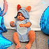Jonas is registered to the contest to win money with this photo: baby, infant, blue_onesie, orange_ears, balloons, blue_balloons, fists_up, curious_expression, sitting, gray_surface, white_backdrop, cute, child, portrait, indoor, plush, soft_texture, happy, young_child, photography