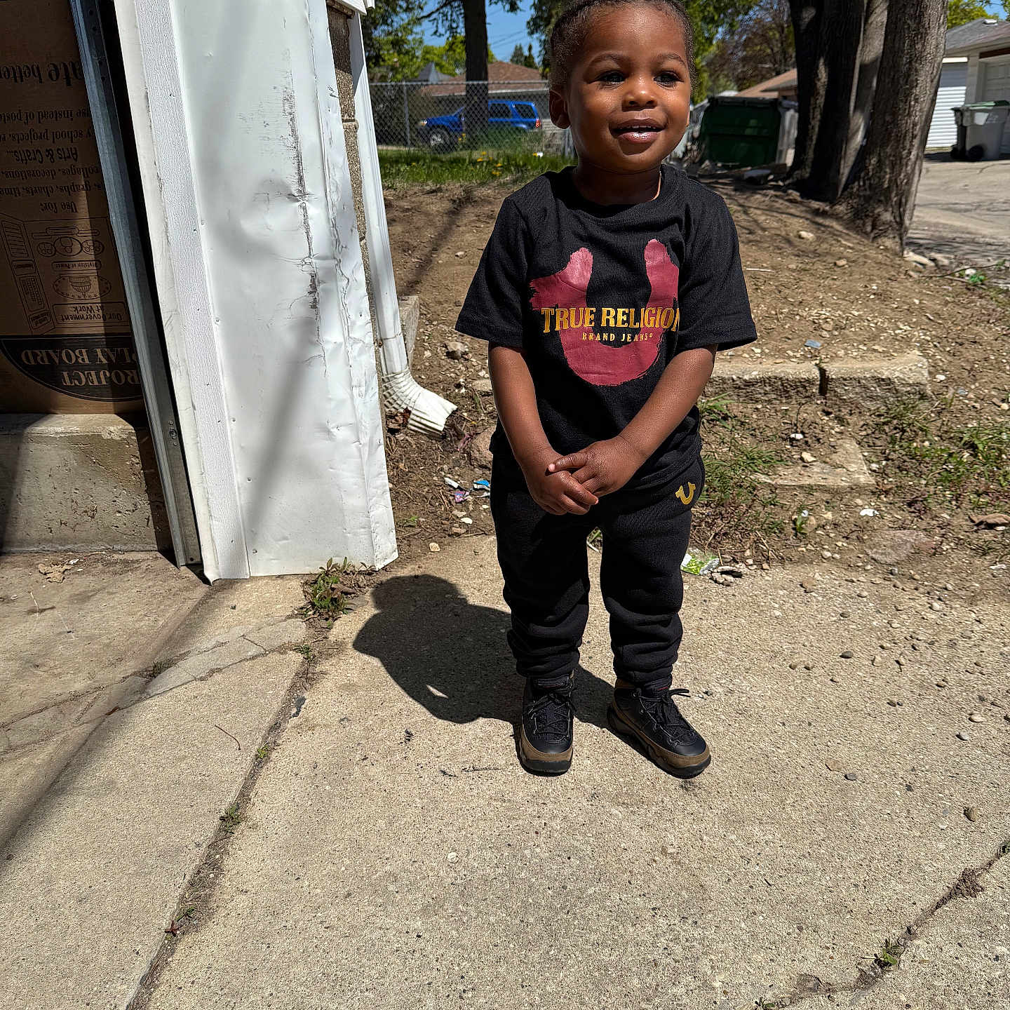 Reighlee joined the competition — help win amazing prizes! black_clothing, building, casual_wear, child, concrete, daylight, happy, outdoor, person, residential_area, shadow, shoes, short_hair, sidewalk, smiling, standing, sunlight, toddler, tree, young_child