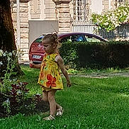 Elyne a rejoint le concours — aidez-le/la à gagner de superbes lots ! child, girl, yellow_dress, flower, grass, outdoor, park, tree, car, building, hedge, sandals, summer, walking, greenery, daylight, nature, cute, side_view, playful