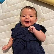 Mila is registered to the contest to win money with this photo: baby, smiling, infant, navy_blue_clothing, mattress, lying_down, cute, happy, child, young_child, indoor, portrait, person, face, skin, hand, head, short_hair, casual_clothing, playful
